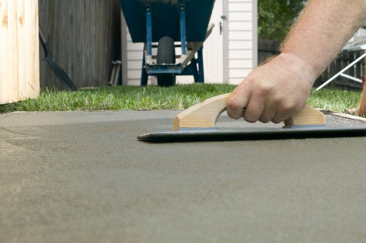 Person troweling wet cement with concrete screed