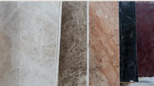 Row of vertical marble sample tiles in beige, brown, peach, black, and burgundy, shown from the side.