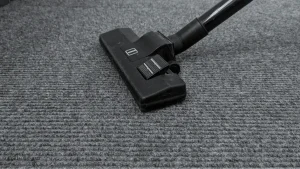 Vacuum cleaner floor head resting on a gray carpet.