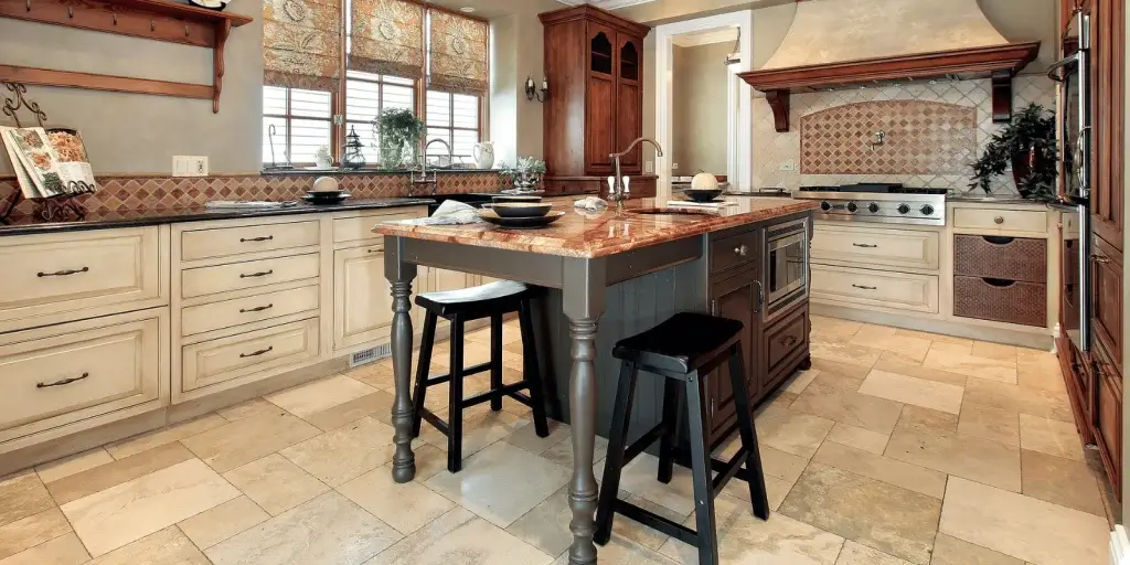 Spacious traditional kitchen with a granite island, cream cabinetry, and two black stools by the island centerpiece.